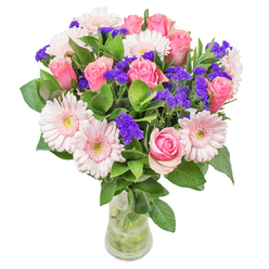 When arranging this bouquet in Chigwell's tranquil atmosphere, I am struck by the ballet of blush-toned gerberas and romantic pink roses, their petals mingling in gentle, watercolour-like layers. Each rose seems to cradle the promise of affection, while sprightly clusters of purple statice dance throughout, providing energetic punctuation without overwhelming the bouquet's soft spirit. The leafy base feels lush and newly gathered, reminiscent of the gardens and avenues found across Chigwell-from Epping Forest's edge to the quaint streets near Brook Parade. Presented in a slim glass vase, the vibrant blooms reflect morning sunlight, casting an irresistible glow that draws the eye and lifts the spirit. This arrangement is not only a cheerful get-well wish or a stylish accent for a home near Chigwell Row but also a testament to craftsmanship-every detail curated to evoke optimism, freshness, and the quiet joys that define our local community. Each element whispers of spring, friendship, and care, making this bouquet a perfect way to connect with loved ones or add a note of brightness to everyday life.